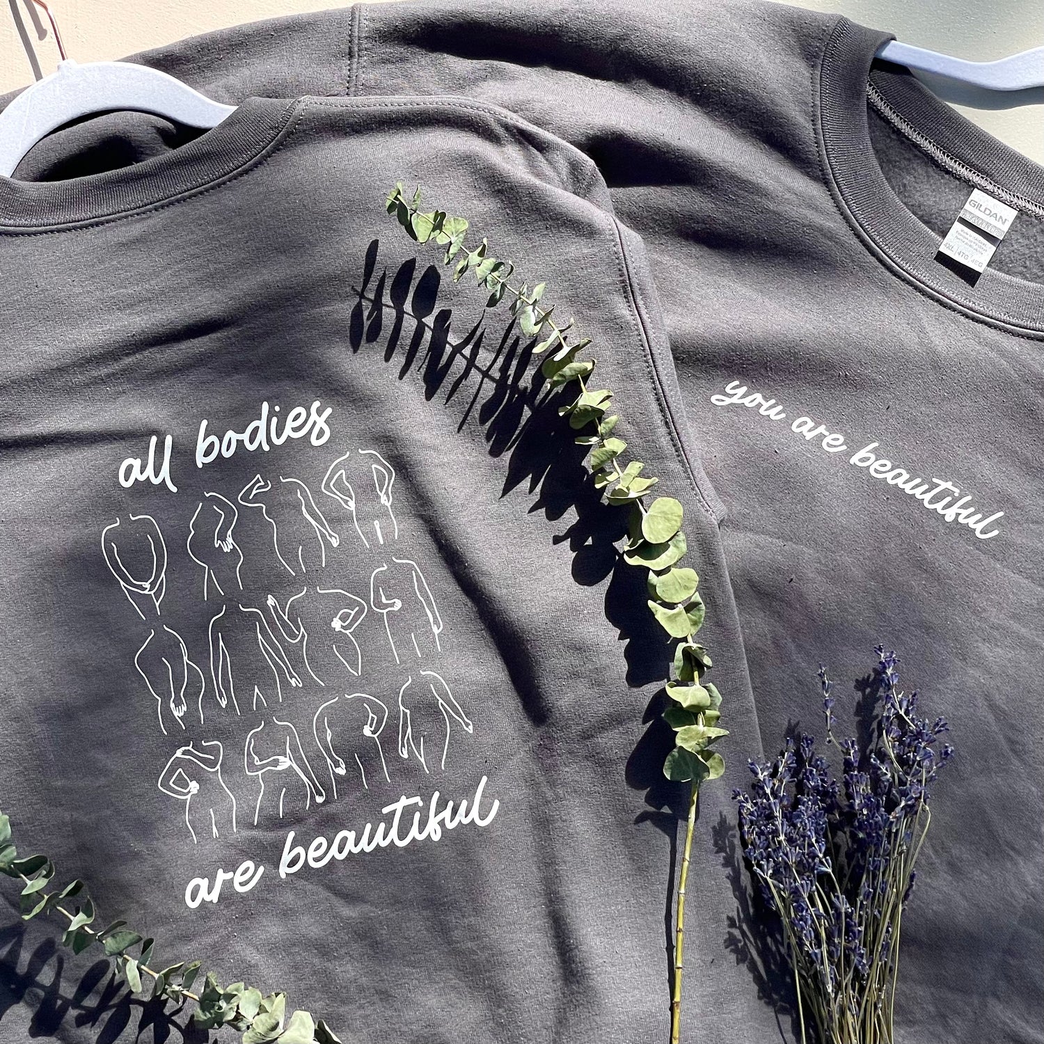 shows a sweatshirt that says you are beautiful on the front and all bodies are beautiful with a bunch of different bodies outlined on the back.